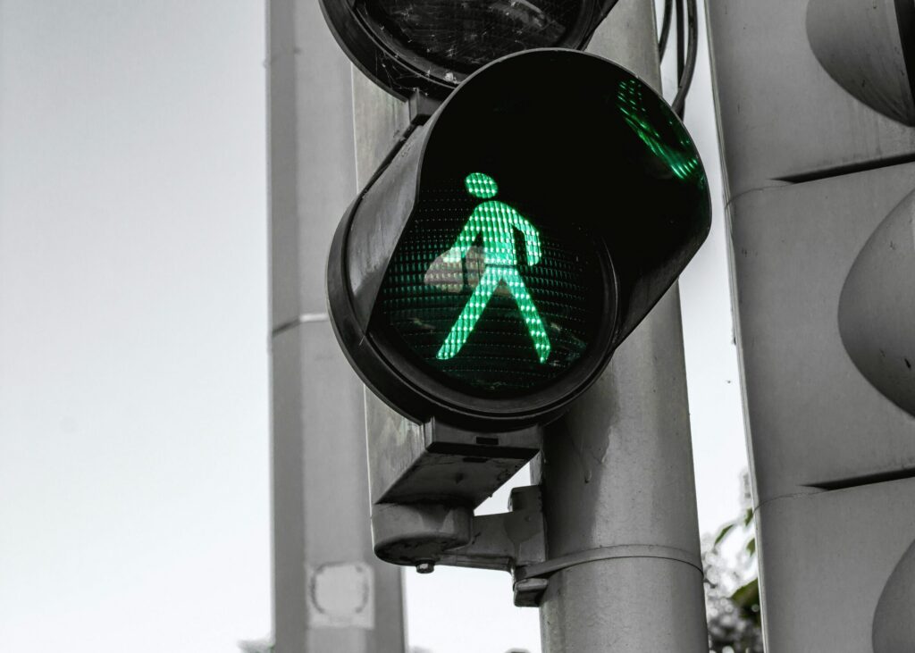 Close-up of a green pedestrian traffic signal indicating walk at an intersection.